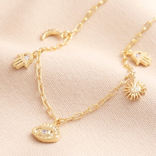 Hamsa Hand Charm Necklace in Gold on a beige fabric