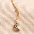 Close Up of Moon Charm on Shell Moon and Star Lariat Necklace in Gold on Beige