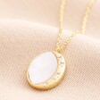 Mother of Pearl Moon Pendant Necklace in Gold against beige background 