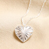 Close up of Sunbeam Heart Pendant Necklace in Silver on beige fabric