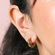 Close up of Shell Crescent Moon Hoop Earrings in Gold on model with dark hair against beige background