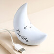 Personalised Smiling Crescent Moon LED Night Light on Beige Platform Showing Cord and Personalisation