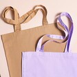Personalised Mirrored Name Tote Bag with purple version on top against beige coloured backdrop