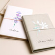 Personalised Birth Flower Vegan Leather Refillable Notebooks in grey and pink stacked on top of beige coloured backdrop