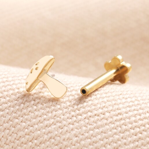 Tish Lyon Solid Gold Toadstool Helix Earring unscrewed next to labret on beige material