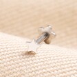 Tish Lyon Solid White Gold Tiny Star Helix Earring on top of beige coloured fabric