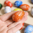 Model Holding Orange Egg From Tony's Chocolonely Egg-stra Special Mix of Chocolate Mini Eggs