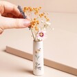 Model placing flowers inside of Tiny Bee Happy Ceramic Bud Vase against beige backdrop