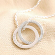 Personalised Sterling Silver Interlocking Crystal Rings Necklace with clean engraving against beige coloured material