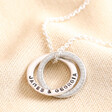 Personalised Sterling Silver Interlocking Crystal Rings Necklace with blackened engraving against neutral fabric