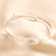 Blackened engraving personalisation on Personalised Sterling Silver Cloud Christening Bangle against neutral fabric