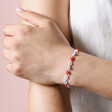 Model with Crossed Arms Wearing Estella Bartlett Red and Blue Daisy Chain Bracelet