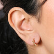 Close Up of Estella Bartlett Crystal Sunburst Huggie Hoop Earrings in Gold on Model