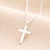 Sterling Silver Small Cross Pendant Necklace on a Beige Background