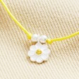 Close Up of Charm on Sterling Silver Yellow Daisy Cord Bracelet on Beige Fabric