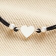 Close Up of Sterling Silver Heart Cord Bracelet on Beige Fabric