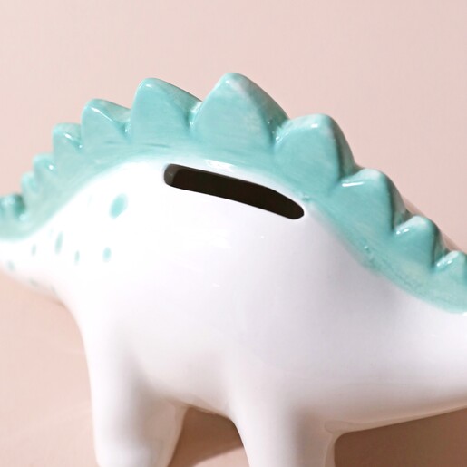 Close up of money slot on Personalised Dinosaur Money Box against beige backdrop