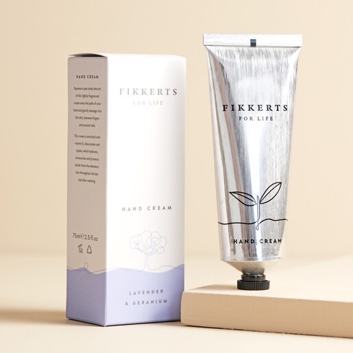 Fikkerts For Life Lavender and Geranium Hand Cream with cream outside of packaging in front of beige backdrop