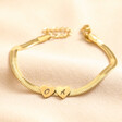 Personalised Gold Stainless Steel Heart Charm Herringbone Bracelet with two heart charms on beige fabric