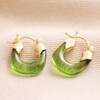 Green Resin Huggie Hoop Earrings in Gold on Beige Fabric