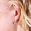 Close up of Encased Pearl Huggie Hoop Earrings in Gold on model