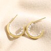 Encased Pearl Huggie Hoop Earrings in Gold on top of beige fabric