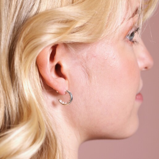 Encased Pearl Huggie Hoop Earrings in Silver on blonde model in front of beige coloured backdrop