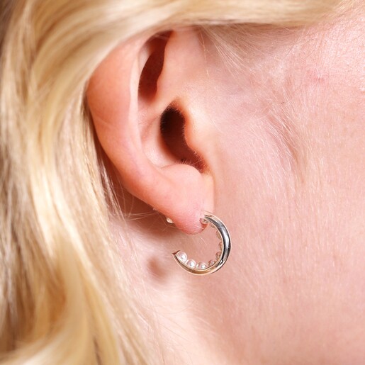 Close up of Encased Pearl Huggie Hoop Earrings in Silver on blonde haired model