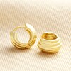 Ridged Huggie Hoop Earrings in Gold on top of beige coloured fabric