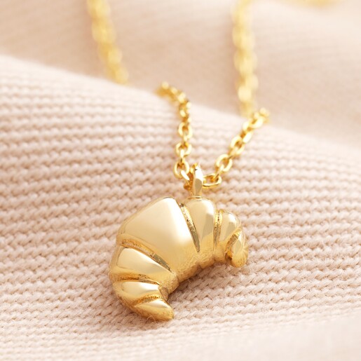 Croissant Pendant Necklace in Gold Croissant Pendant Necklace in Gold on Beige Fabric