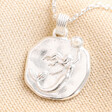Close Up of Mermaid Coin Pendant Necklace in Silver on beige fabric