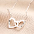 Silver Version of Personalised Interlocking Hearts Necklace on beige fabric