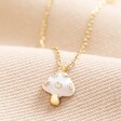 White Enamel Mushroom Pendant Necklace in Gold on Beige Fabric