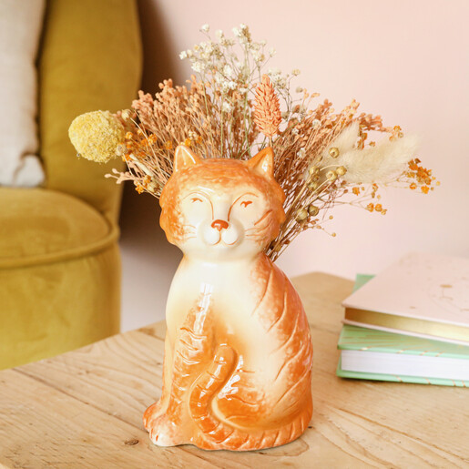 Tigger the Orange Cat Vase Close up of Tigger the Orange Cat Vase face sitting on table with flowers behind