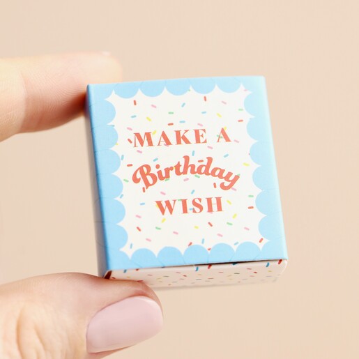 Model holding Tiny Matchbox Ceramic Birthday Cake Token in front of beige background