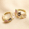 Multicoloured Enamel Floral Huggie Hoop Earrings in Gold on Beige Fabric