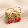 Enamel Red Cherry Charm Huggie Hoop Earrings in Gold on Beige Fabric