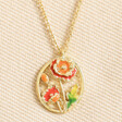 Close up of august Enamel Birth Flower Outline Pendant Necklace in Gold against neutral fabric