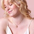 Enamel Birth Flower Outline Pendant Necklace in Gold on model smiling against pink backdrop