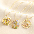 Three Enamel Birth Flower Outline Pendant Necklaces in Gold laid on top of neutral fabric