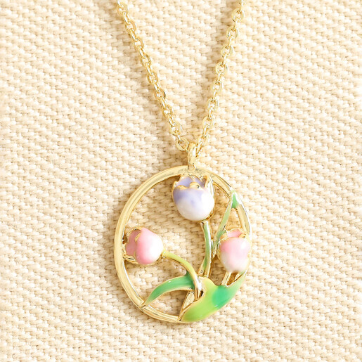 Close up of may Enamel Birth Flower Outline Pendant Necklace in Gold against neutral fabric