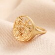 Adjustable Matte Floral Signet Ring in Gold on top of beige coloured material