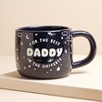Ceramic Midnight Blue Best Daddy in the Universe Mug on raised surface against beige backdrop