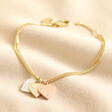 Personalised Mixed Metal Heart Bracelet in gold with mixed metal pendants against beige fabric