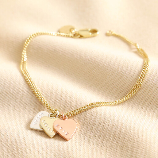 Mixed Metal Personalised Mixed Metal Heart Bracelet in gold with mixed metal pendants against beige fabric