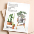 Back of How to Raise a Plant and Make it Love You Back Book against neutral backdrop