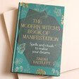 The Modern Witch's Book of Manifestation on Pink Surface