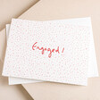 Heather Evelyn Confetti Engagement Card on top of envelope on pink surface