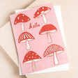 Heather Evelyn Hello Mushroom Greetings Card with Envelope on Pink Surface