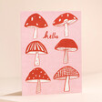 Heather Evelyn Hello Mushroom Greetings Card on Pink Surface